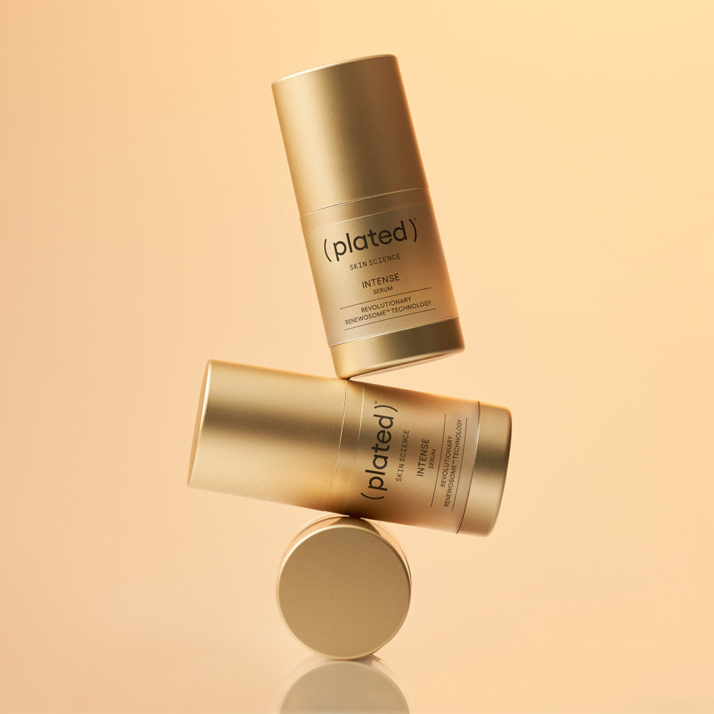 Three gold skincare serum bottles labeled ( plated ) Skin Science INTENSE SERUM on a beige/gold background